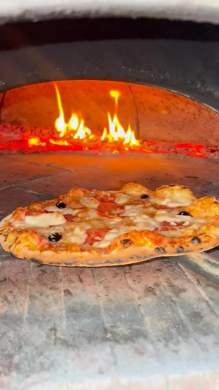 Pizza en cuisson dans le four à bois